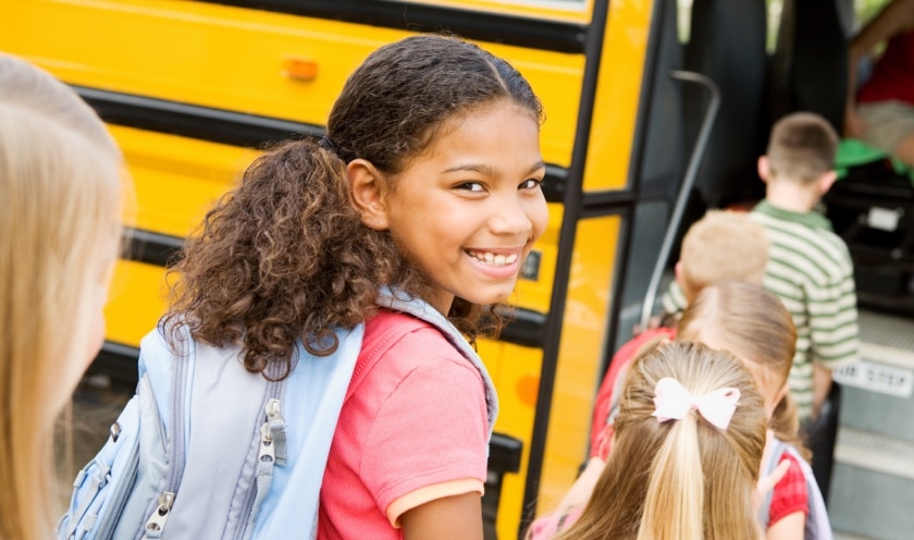 Girl smiling while getting on a school bus